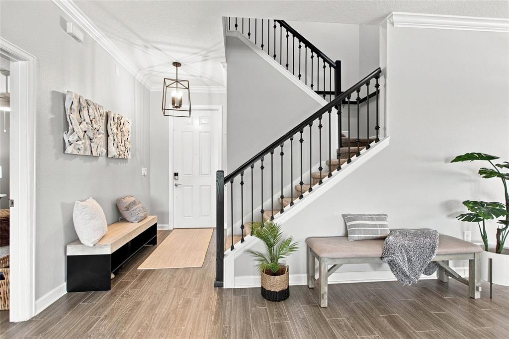 A bright entryway features a staircase with black railings, wood-look flooring, and two benches — 8871 BACKSPIN LANE, DAVENPORT, FL