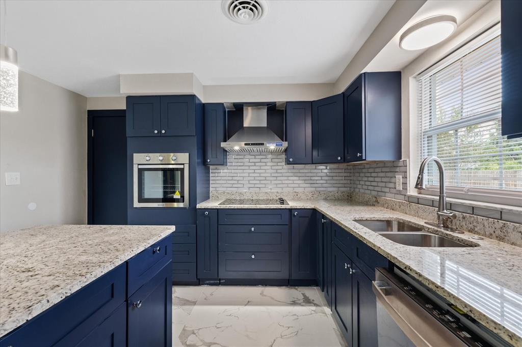 A kitchen with navy blue cabinets, granite countertops, stainless steel appliances, and white marble flooring — 5900 AVOCADO STREET, ZEPHYRHILLS, FL