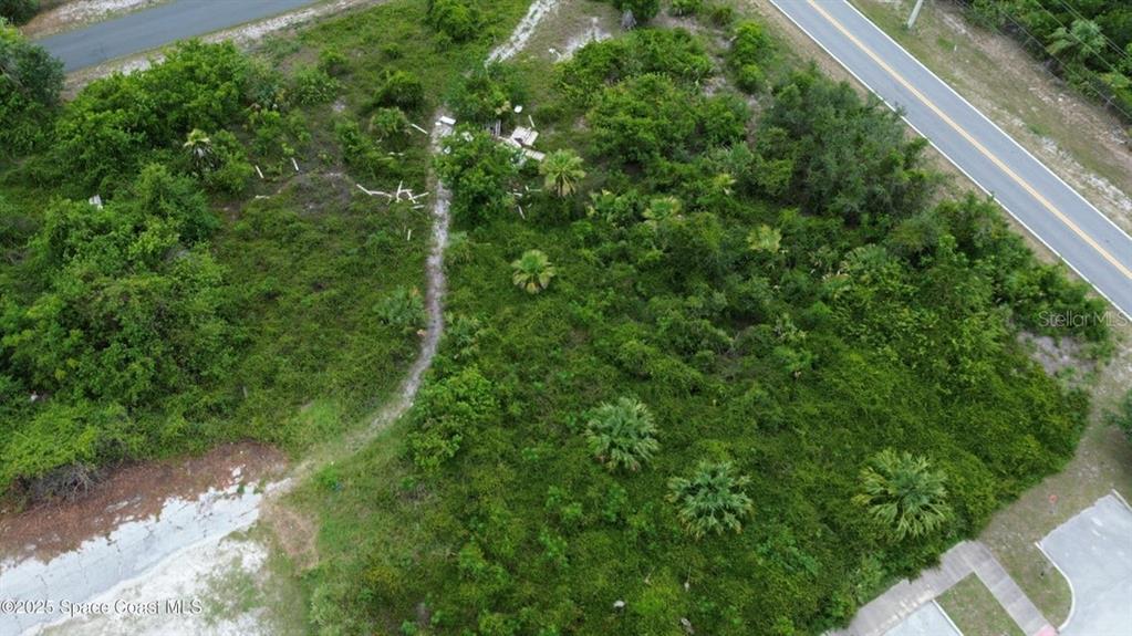 An aerial view shows a vacant, heavily wooded lot bordered by two paved roads — 3765 KINGS HIGHWAY, COCOA, FL