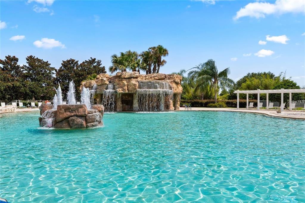 A swimming pool features a large rock waterfall and a smaller fountain in the center — 5418 COMPASS POINT, OXFORD, FL