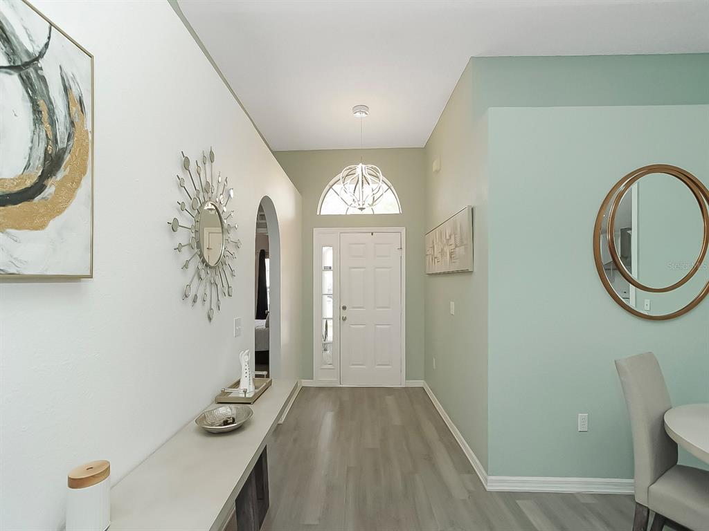 A bright entryway features light wood flooring, a white front door, and decorative wall mirrors — 2927 ELBIB DR, ST CLOUD, FL