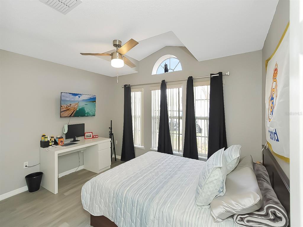 A bedroom features a bed, a desk with a computer, and a vaulted ceiling — 2927 ELBIB DR, ST CLOUD, FL