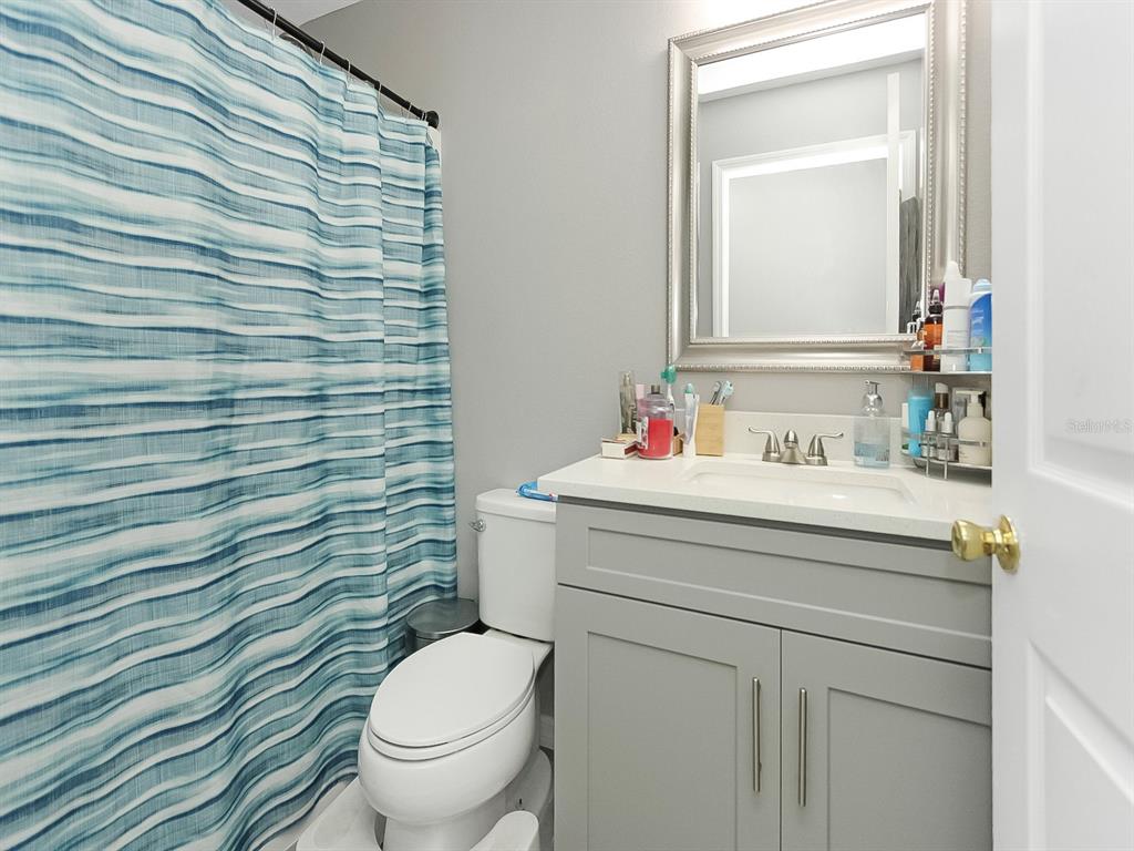 A bathroom features a gray vanity, a white toilet, and a blue-striped shower curtain — 2927 ELBIB DR, ST CLOUD, FL
