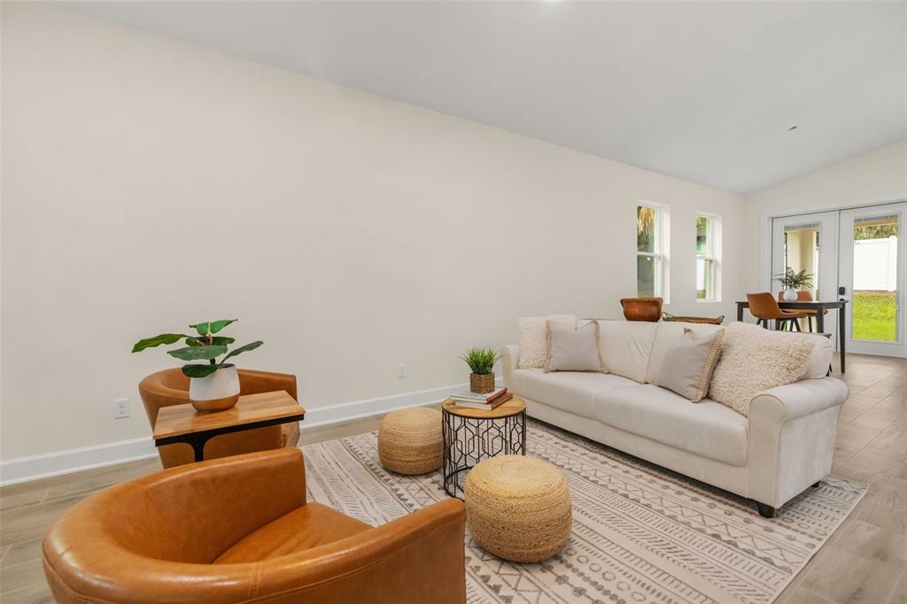 A living room features a white sofa, two leather chairs, and a patterned area rug — 221 S SUNSET AVENUE, MASCOTTE, FL