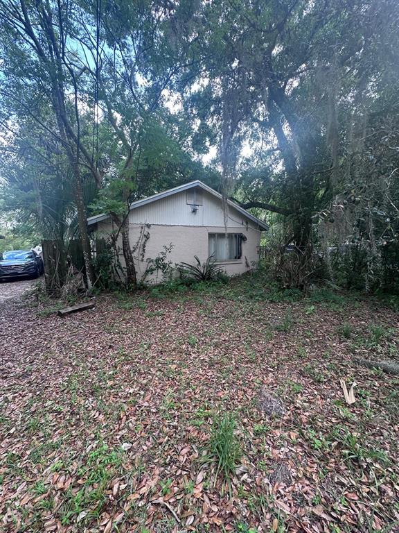A single-story house with beige stucco siding sits among mature trees covered in Spanish moss — 3412 ORANOLE ROAD, ORLANDO, FL