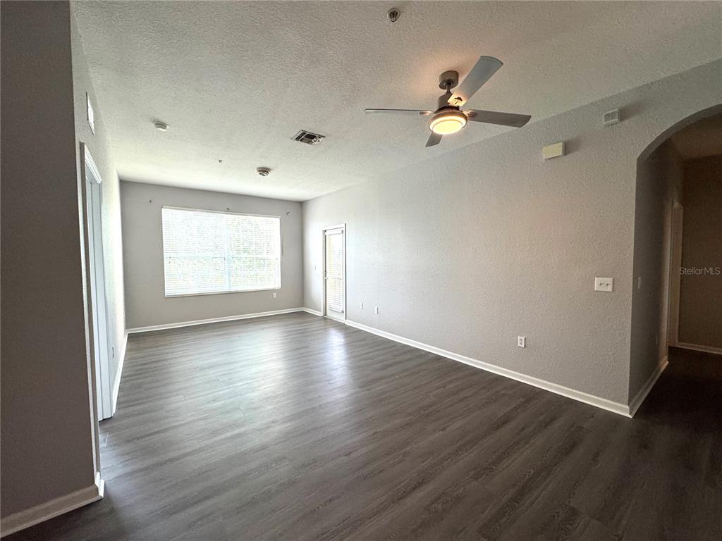 An empty bedroom features gray walls, dark wood-look flooring, a ceiling fan, and a window — 8660 BUCCILLI DRIVE UNIT 305, ORLANDO, FL