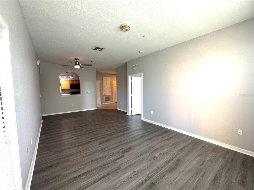 A tiled entryway leads to a living area with dark flooring and an arched kitchen doorway — 8660 BUCCILLI DRIVE UNIT 305, ORLANDO, FL