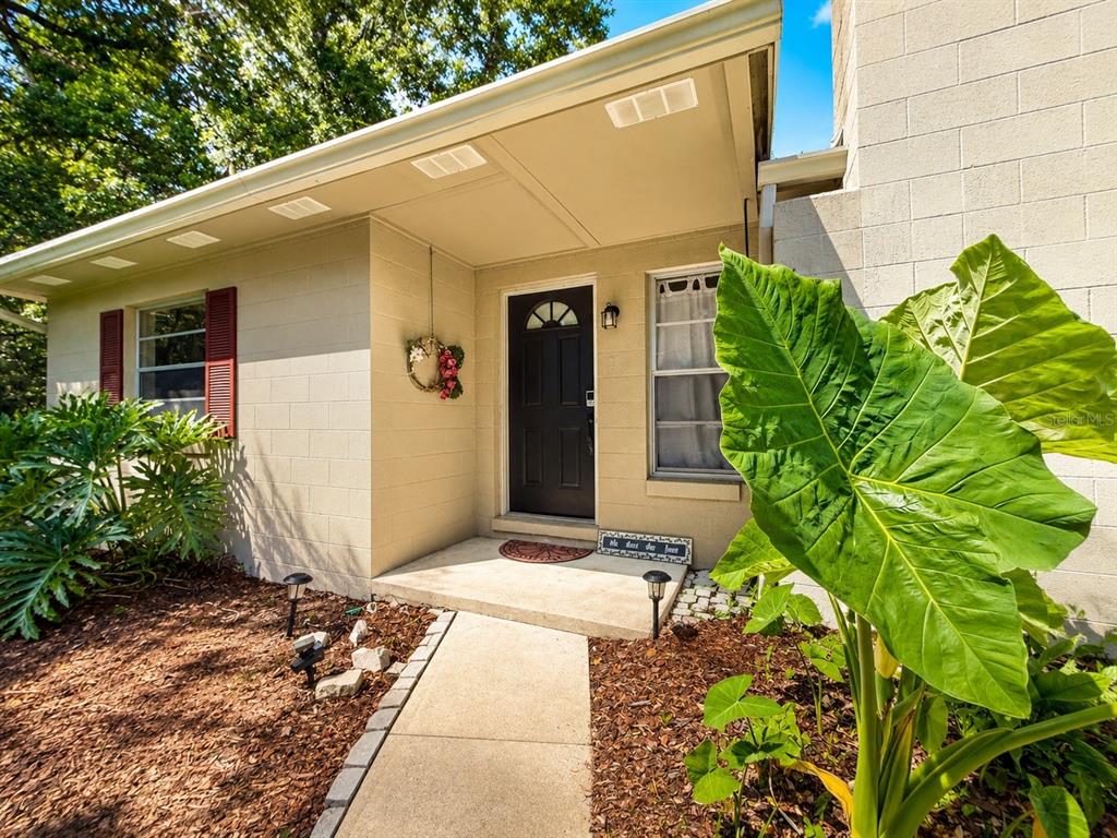 A concrete walkway leads to the front entrance of a house with a block exterior — 410 RUBY AVENUE, DELAND, FL