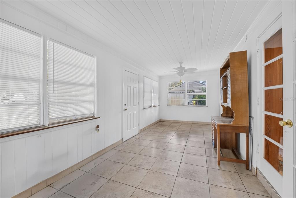 A sunroom with white paneled walls, tiled flooring, a ceiling fan, and a wooden hutch — 12345 SE 135TH COURT, OCKLAWAHA, FL