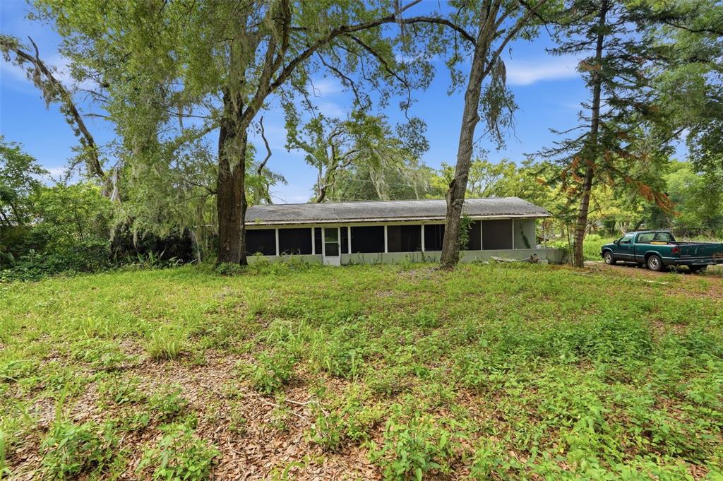 A single-story house with a screened porch sits on a grassy lot with large trees — 832 S PARSONS AVENUE, BRANDON, FL