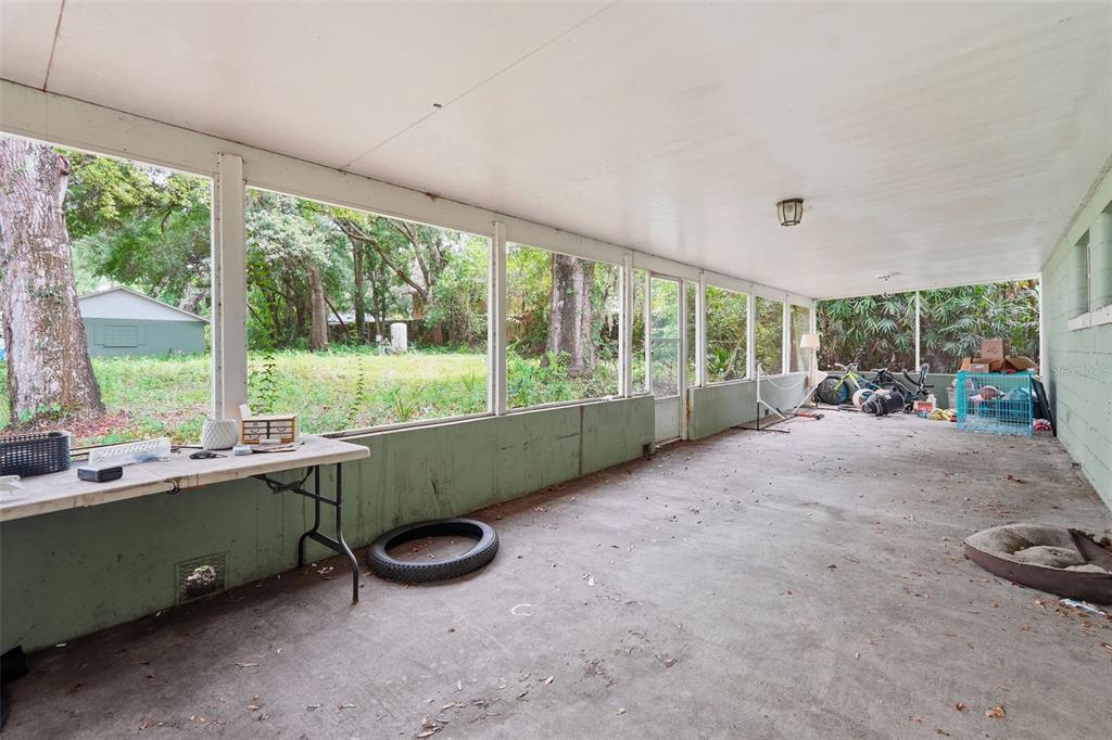 A large, covered screened-in porch with a concrete floor and views of a wooded backyard — 832 S PARSONS AVENUE, BRANDON, FL