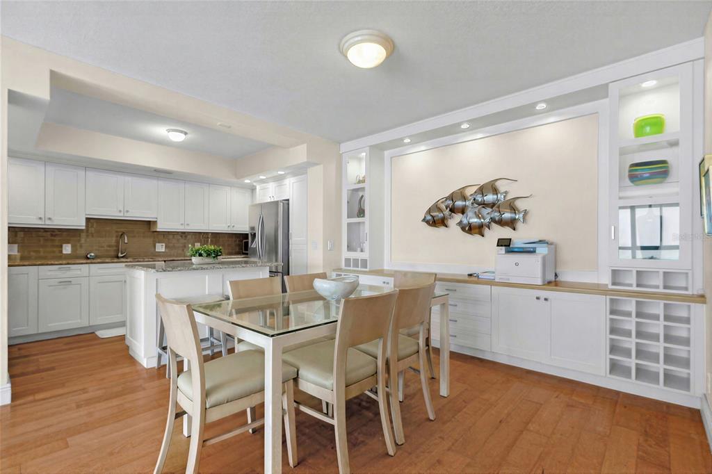 A dining area with a glass table, light wood chairs, and built-in white cabinetry — 3820 GULF BOULEVARD UNIT 1205, ST PETE BEACH, FL
