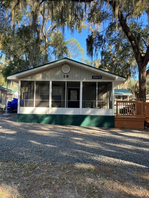 A single-story mobile home with a screened-in front porch and a gravel driveway — 25079 NE 140TH LOOP, SALT SPRINGS, FL