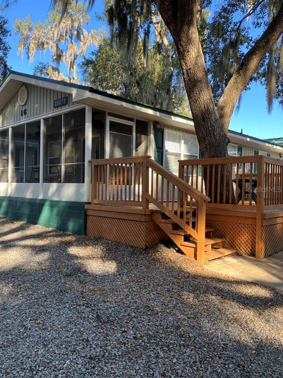 A mobile home exterior features a screened-in porch, a wooden deck, and a large tree — 25079 NE 140TH LOOP, SALT SPRINGS, FL