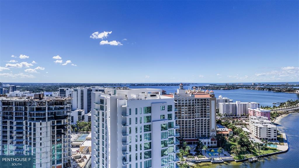 An aerial view shows high-rise buildings, a construction site, and a waterfront area under a blue sky — 555 QUAY COMMONS UNIT 2001, SARASOTA, FL