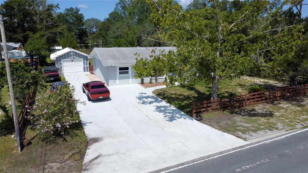 An aerial view shows a light-colored house with a detached garage and a concrete driveway — 8301 WEEPING WILLOW STREET, BROOKSVILLE, FL