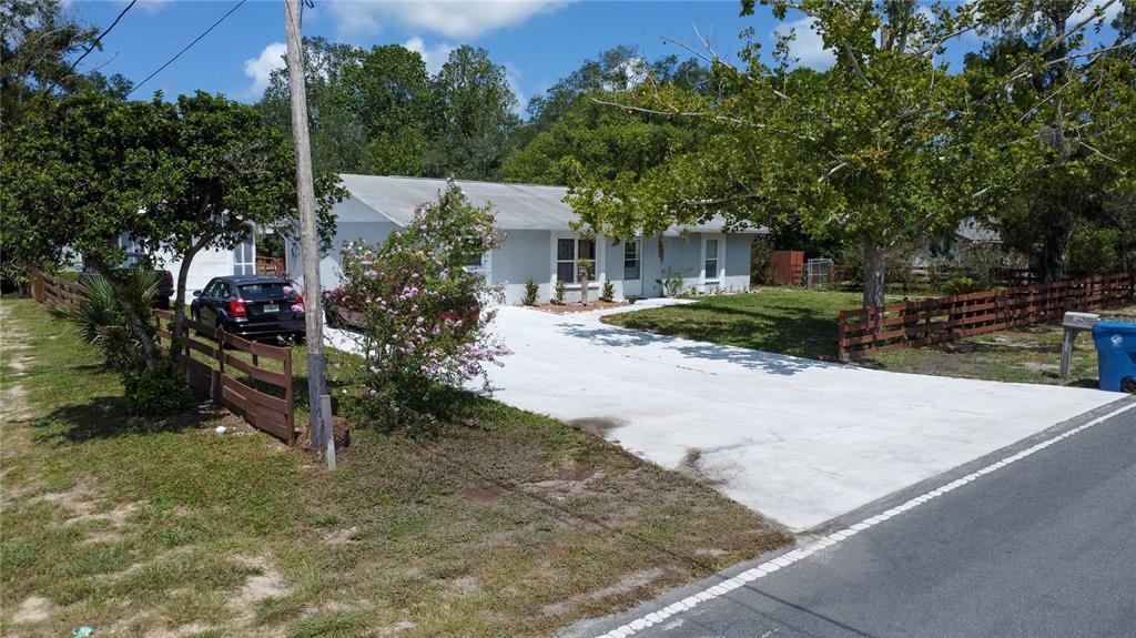 A single-story house with a white exterior, a concrete driveway, and a wooden fence — 8301 WEEPING WILLOW STREET, BROOKSVILLE, FL