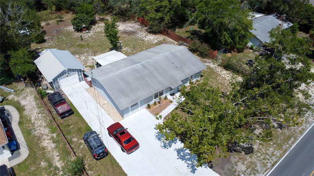 An aerial view shows a single-story house with a detached garage and two parked cars — 8301 WEEPING WILLOW STREET, BROOKSVILLE, FL