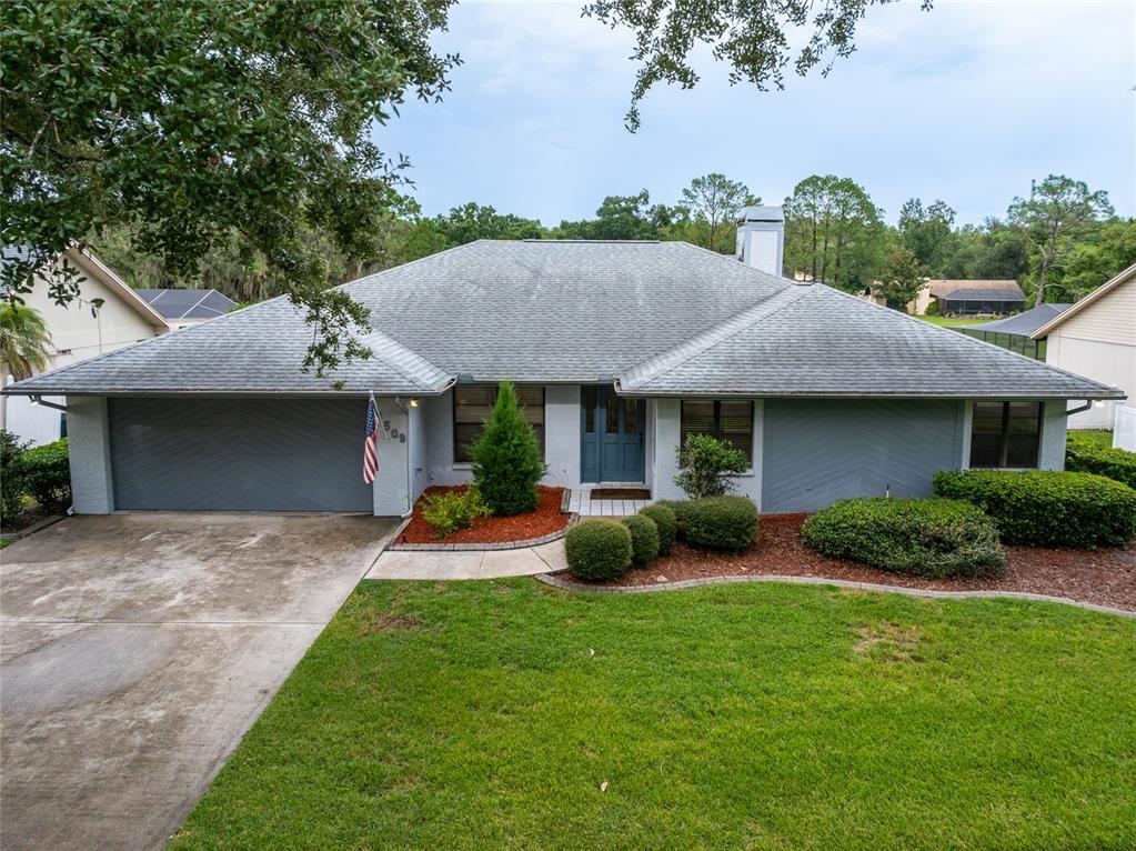 A single-story house with a gray exterior, a two-car garage, and a landscaped front yard — 16509 E COURSE DRIVE, TAMPA, FL