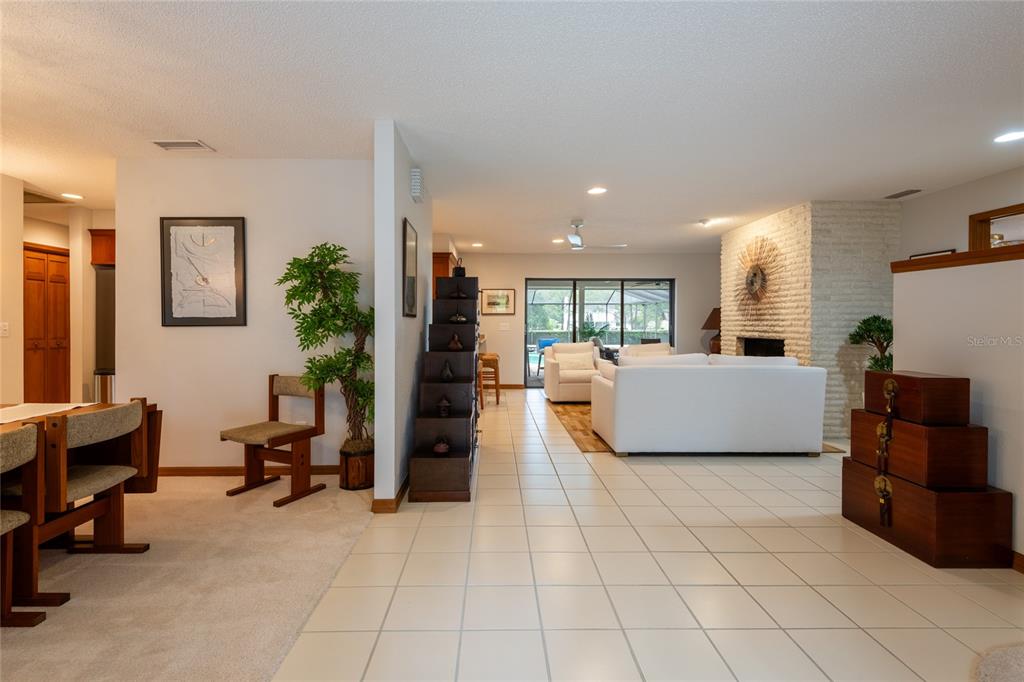 A living room and dining area feature white tile flooring, a brick fireplace, and furniture — 16509 E COURSE DRIVE, TAMPA, FL