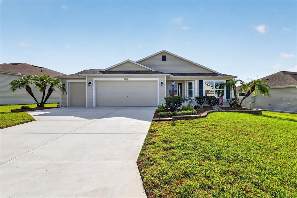 A single-story house with a beige exterior, a three-car garage, and a landscaped front yard — 3305 FINK STREET, THE VILLAGES, FL