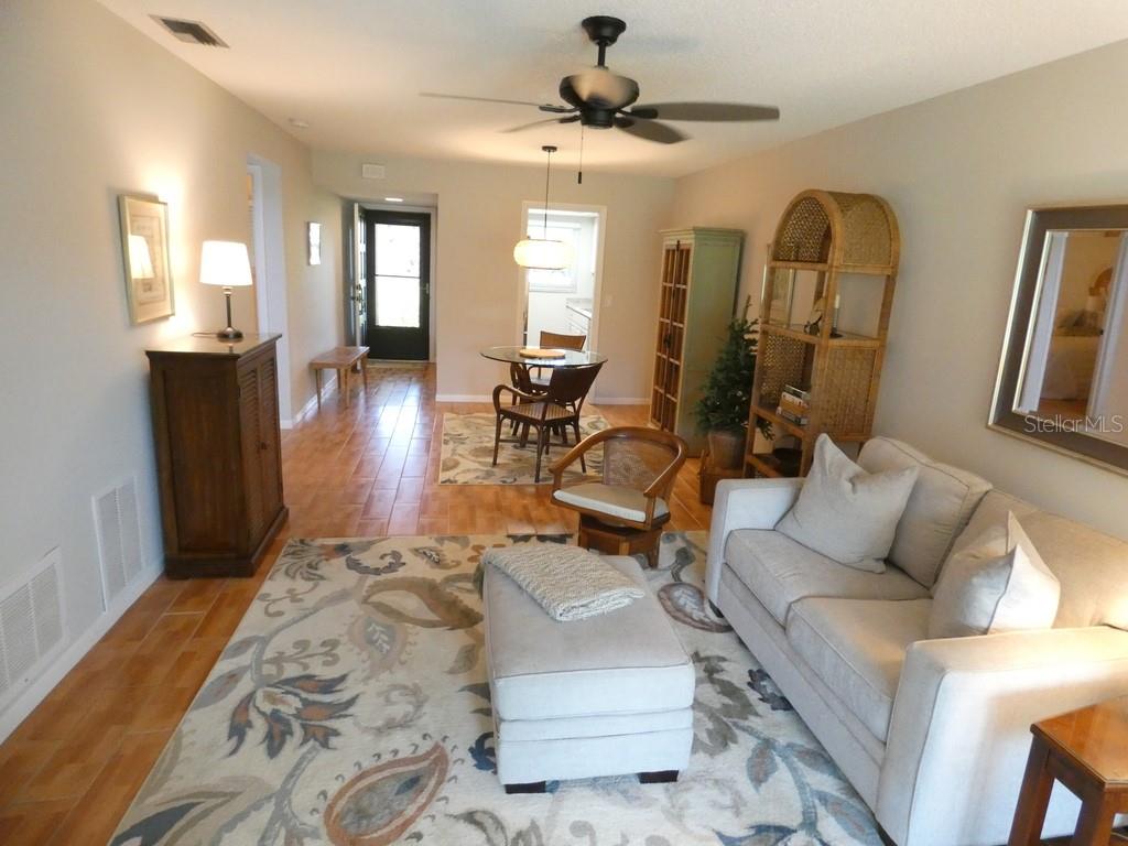 A living room and dining area feature tile floors, a ceiling fan, and area rugs — 1701 PINEHURST ROAD UNIT 9G, DUNEDIN, FL