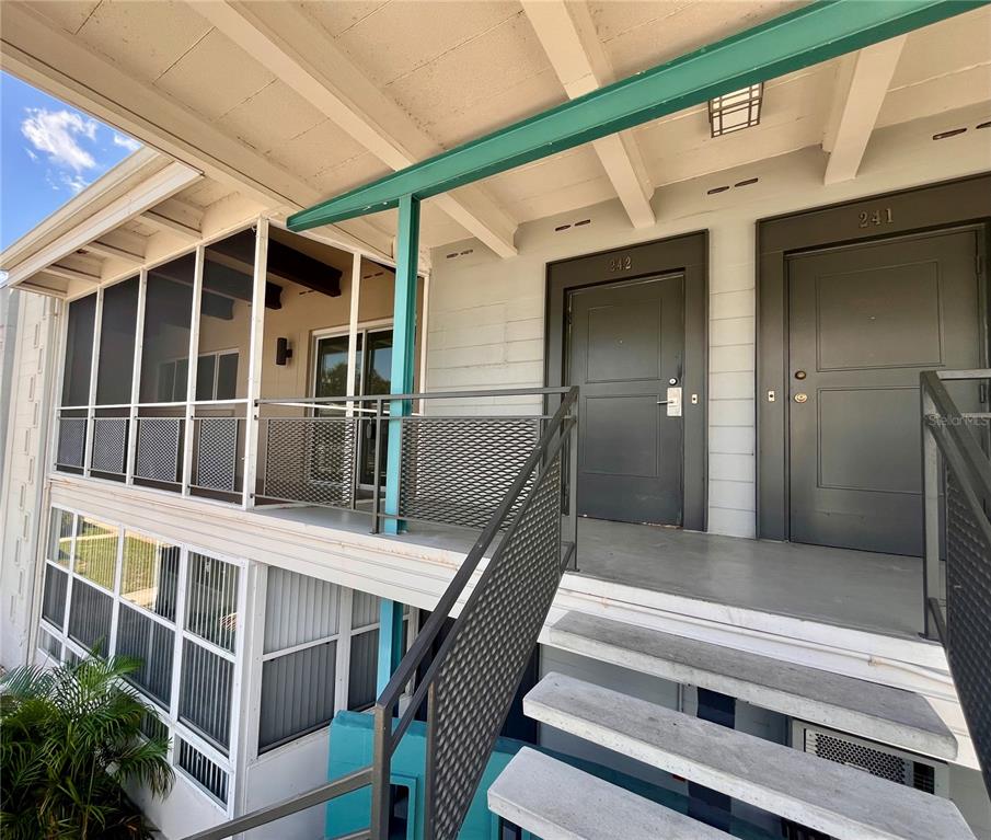 An exterior view of an apartment building with a screened balcony, stairs, and two doors — 151 N ORLANDO AVENUE UNIT 242, WINTER PARK, FL
