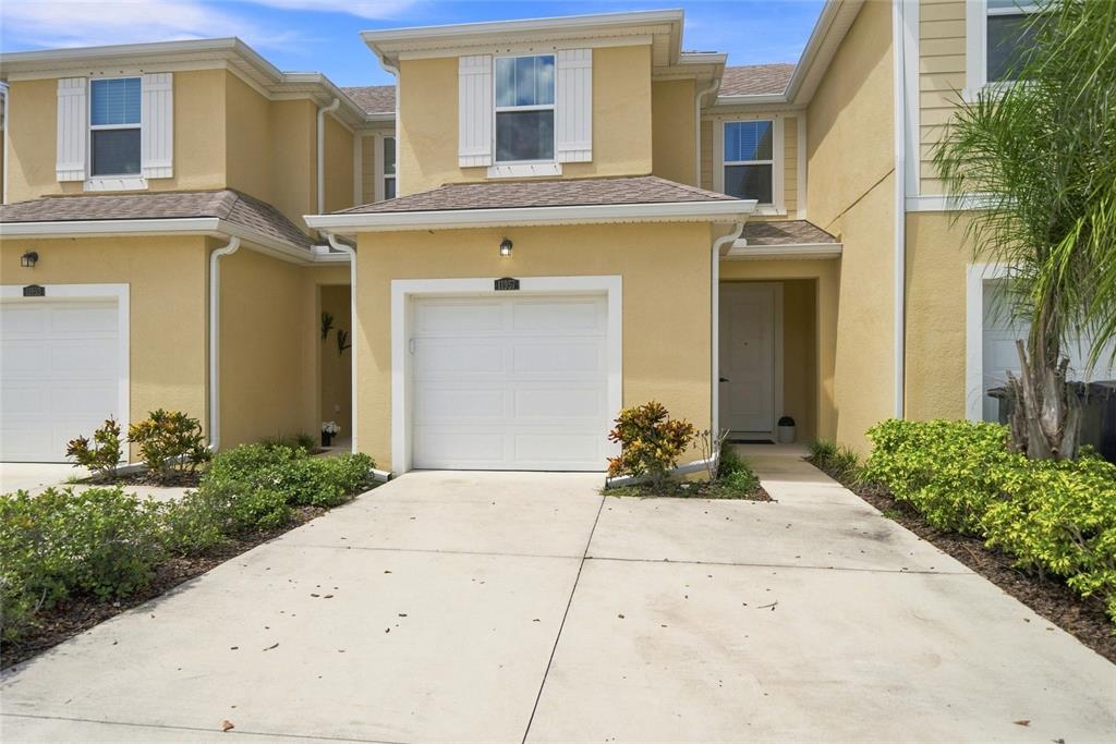A two-story yellow townhouse with a single-car garage and a concrete driveway — 11957 SKY ACRES TERRACE, LAKEWOOD RANCH, FL