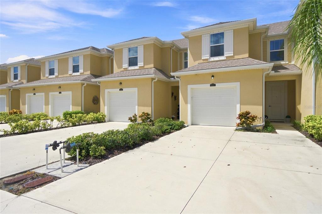 A row of tan two-story townhouses features white garage doors and concrete driveways — 11957 SKY ACRES TERRACE, LAKEWOOD RANCH, FL