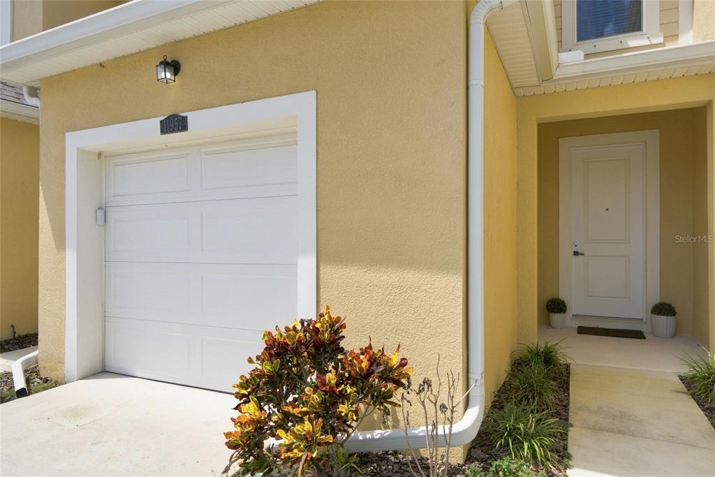 A yellow stucco house exterior features a white garage door and a front entryway — 11957 SKY ACRES TERRACE, LAKEWOOD RANCH, FL
