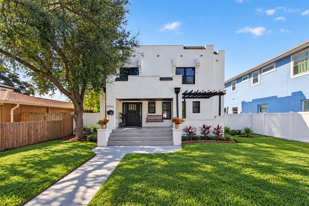A white two-story house with a front porch, pergola, and a grassy front yard — 6566 1ST AVENUE S, ST PETERSBURG, FL
