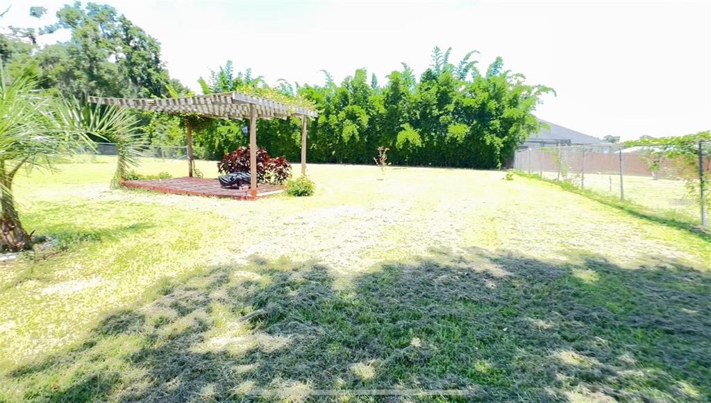 A large grassy backyard features a wooden pergola over a deck and a chain-link fence — 0 N US HIGHWAY 441, OCALA, FL