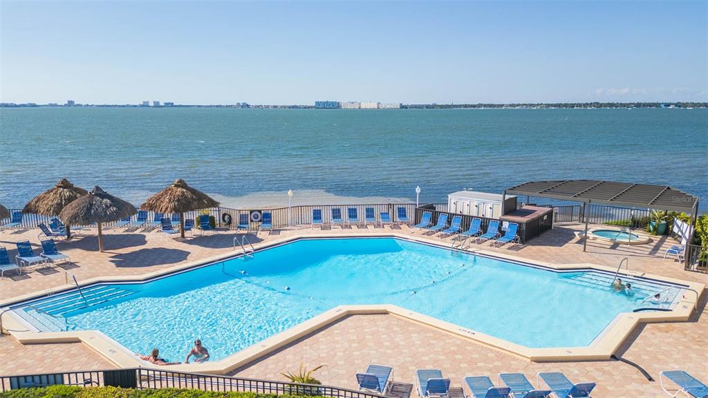 An elevated view of a swimming pool overlooking the ocean with lounge chairs and umbrellas — 5633 PUERTA DEL SOL BOULEVARD S UNIT 208, ST PETERSBURG, FL