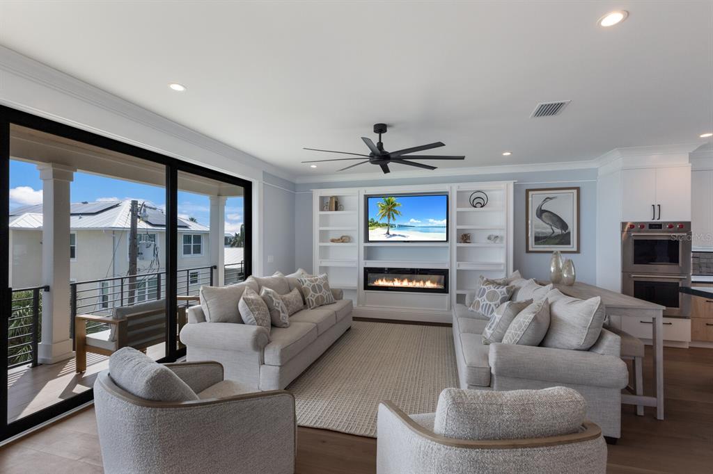 A living room features two sofas, two armchairs, a fireplace, and a balcony view — 2415 AVENUE B, BRADENTON BEACH, FL