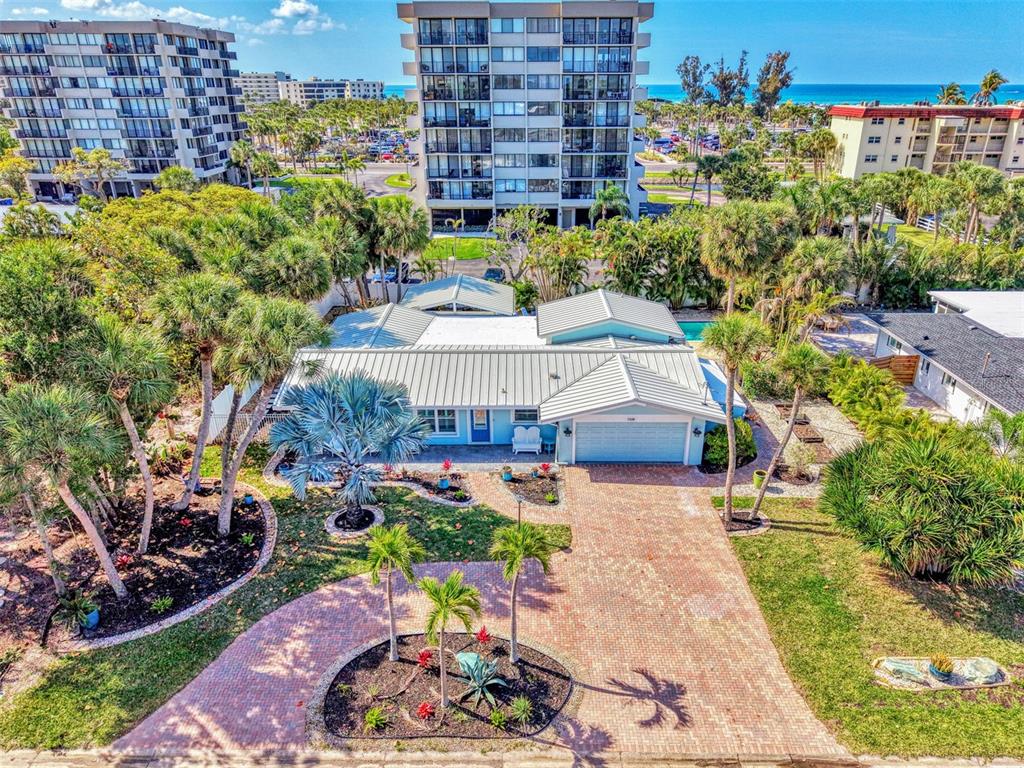 An aerial view shows a single-story house with a metal roof, brick driveway, and landscaping — 5628 CAPE LEYTE DRIVE, SARASOTA, FL
