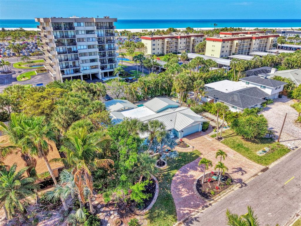 An aerial view shows a single-story house with a metal roof near the beach — 5628 CAPE LEYTE DRIVE, SARASOTA, FL