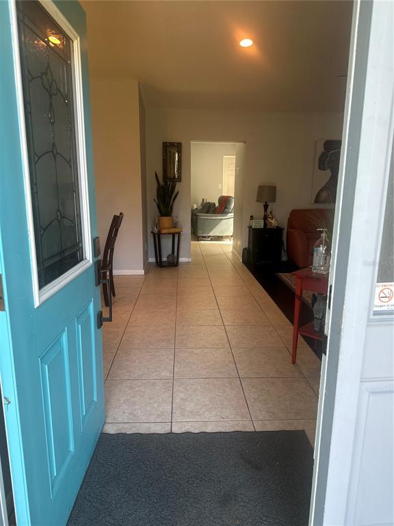 A view from an open turquoise front door into a tiled living area and dining space — 2527 10TH AVENUE S, ST PETERSBURG, FL