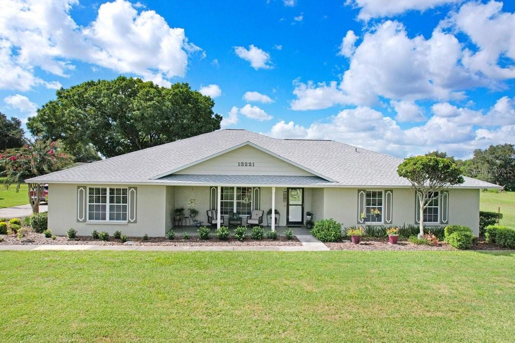 A single-story house with a light-colored exterior, a covered front porch, and a large lawn — 13221 TOM GALLAGHER ROAD, DOVER, FL