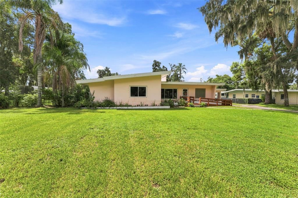 A single-story, light-pink house with a slanted roof sits on a large, grassy lawn — 1311 E TOMLIN STREET, PLANT CITY, FL