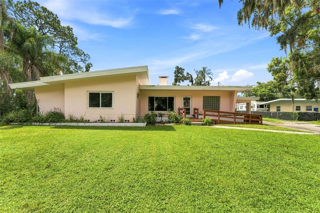 A single-story, light pink house with a flat roof and a wooden wheelchair ramp — 1311 E TOMLIN STREET, PLANT CITY, FL
