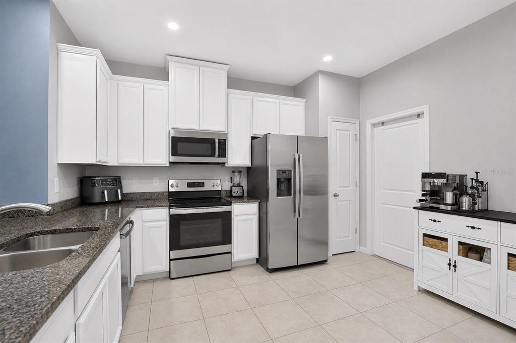 A kitchen with white cabinets, stainless steel appliances, granite countertops, and light tile flooring — 2911 JACOB CROSSING LANE, HOLIDAY, FL