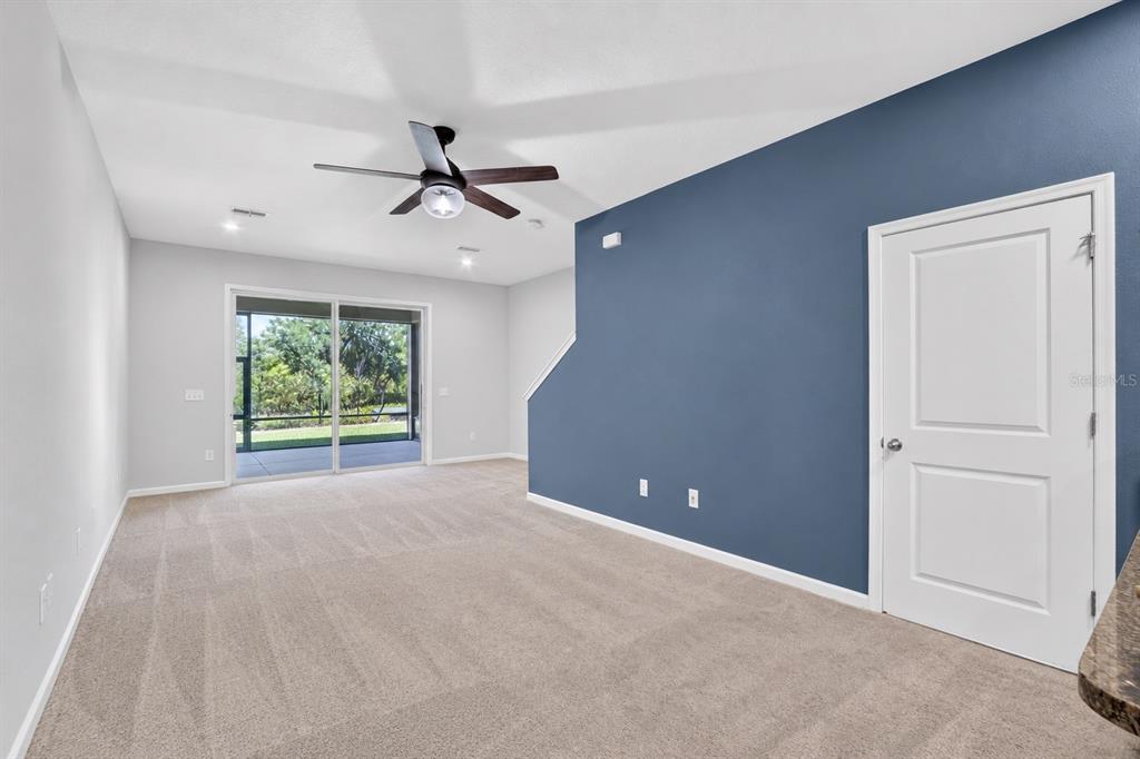 A living room features a grey sectional sofa, a blue accent wall, and a television — 2911 JACOB CROSSING LANE, HOLIDAY, FL