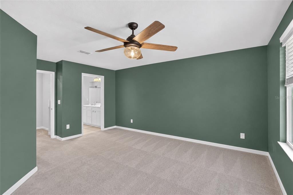 A bedroom features dark green walls, a light wood bed frame, and a ceiling fan — 2911 JACOB CROSSING LANE, HOLIDAY, FL