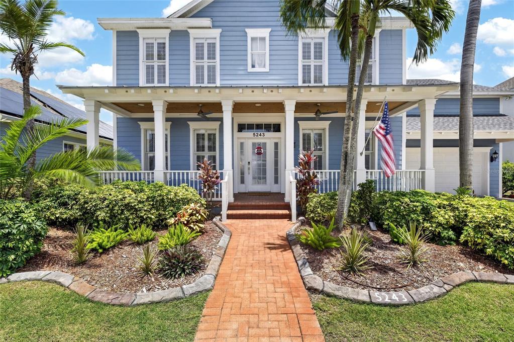 A two-story blue house with a front porch, brick walkway, and palm trees — 5243 BRIGHTON SHORE DRIVE, APOLLO BEACH, FL