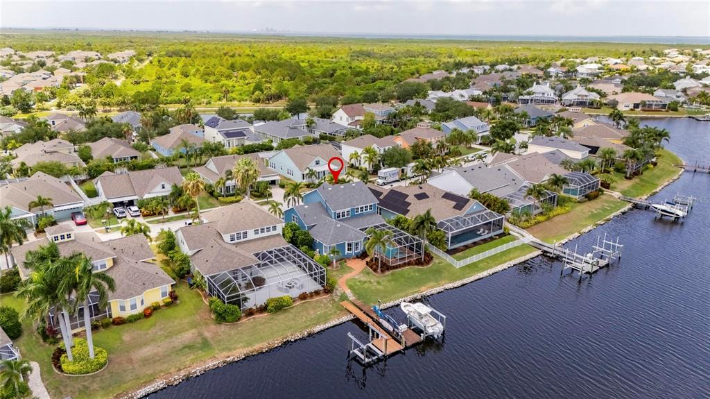 An aerial view shows a blue waterfront house with a private dock and solar panels — 5243 BRIGHTON SHORE DRIVE, APOLLO BEACH, FL