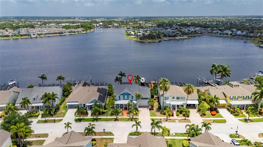 An aerial view shows a blue waterfront house with a red location pin — 5243 BRIGHTON SHORE DRIVE, APOLLO BEACH, FL
