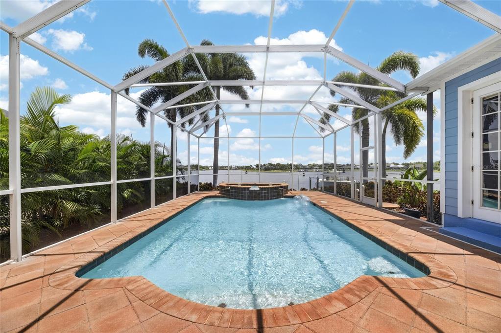 A screened-in pool and spa area with a brick paver deck overlooking a lake — 5243 BRIGHTON SHORE DRIVE, APOLLO BEACH, FL