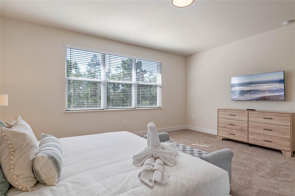 A bedroom features a bed with a towel swan, a dresser, and a wall-mounted television — 17244 BLESSING DRIVE, CLERMONT, FL
