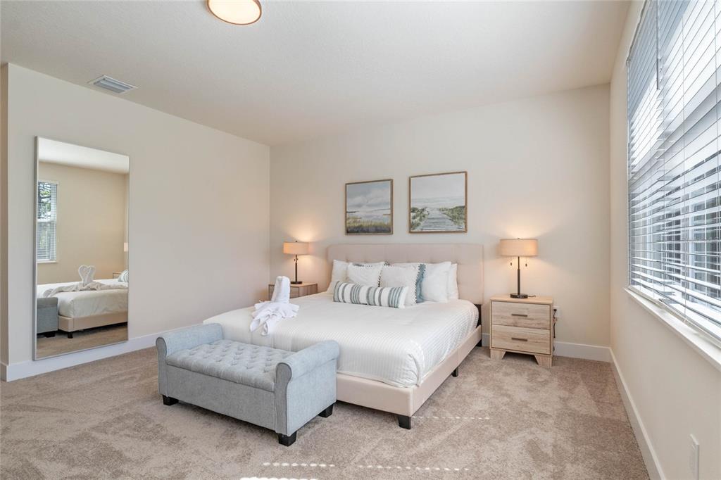 A bedroom features a bed with a light-colored headboard, two nightstands, and a floor mirror — 17244 BLESSING DRIVE, CLERMONT, FL