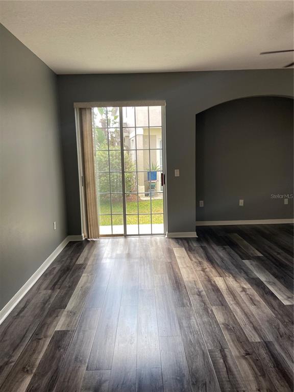 A room with gray walls, wood-look flooring, and a sliding glass door leading outside — 27546 PLEASURE RIDE LOOP, WESLEY CHAPEL, FL
